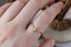 A dramatically tapered ring with leaves and a rustic carved band is topped with a pear cut diamond. Designed by The North Way Studio and shown here in yellow gold on a woman's hand.