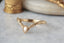 A dramatically tapered ring with leaves and a rustic carved band is topped with a pear cut diamond. Designed by The North Way Studio and shown here in yellow gold.