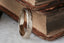 The Elder King Band by The North Way Studio is a hand-carved golden wedding band, shown here in a close up image leaning against antique books atop a white marble tabletop.