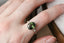 A fantasy engagement ring featuring a dark forest green natural oval brilliant cut sapphire, two marquise diamonds, and hand-carved leaf and bark texture in reclaimed 18 karat white gold. This fairytale garden engagement ring is ready to ship, size 6 1/2. Crafted by The North Way Studio in collaboration with Claire Pettibone.