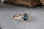 A large blue sapphire sits in the middle of this ready to ship engagement ring designed by The North Way Studio shown facing slightly right. A halo of diamonds surrounds the center stone. The band is hand-carved reclaimed gold.