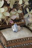 A blue sapphire ring with diamonds designed and crafted by The North Way Studio in collaboration with Claire Pettibone and cast in reclaimed gold is shown sitting upon an antique jewelry box.