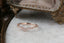 A ring made of a faintly curved rivulet of rose cut natural diamonds nestled against a hand-carved band of unfurling leaves and bark. Designed by The North Way Studio and shown here atop a white marble tabletop. 