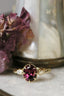 Marquise diamonds and unfurling carved gold leaves nestle a uniquely chosen center stone in this heirloom engagement ring setting designed and crafted by The North Way Studio. This ethereal engagement ring is shown cast in 14 karat yellow gold with an oval deep berry spinel center and resting on a marble surface.