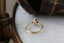 Petite claw prongs embrace a lab grown pear cut diamond in this ready to ship engagement ring designed by The North Way Studio. The band is gold and hand-carved with leaves and bark. Facing away from the viewer.