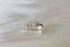 A small gold charm with lab grown pear diamond and hand-carved leaf details. Shown in white gold in a close up of a leaf.