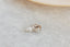A small gold charm with lab grown diamond and hand-carved leaf details. 