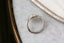 A solitaire fantasy engagement ring crafted by The North Way Studio. This fairytale ring features a lab grown marquise diamond, an engraved shield setting, and organic carvings in the gold on one side. Shown in 14 karat white gold. Shown viewed from above with the smooth side up.