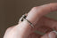 A solitaire fantasy engagement ring crafted by The North Way Studio. This fairytale ring features a lab grown marquise diamond, an engraved shield setting, and organic carvings in the gold on one side. Shown in 14 karat white gold. Shown is the side profile while worn on the hand.