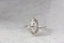 A solitaire fantasy engagement ring crafted by The North Way Studio. This medieval inspired ring features a lab grown marquise diamond, an engraved shield setting, and organic carvings in the gold on one side. Shown in 14 karat white gold.