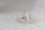 A solitaire fantasy engagement ring crafted by The North Way Studio. This medieval inspired ring features a lab grown marquise diamond, an engraved shield setting, and organic carvings in the gold on one side. Shown in 14 karat white gold.
