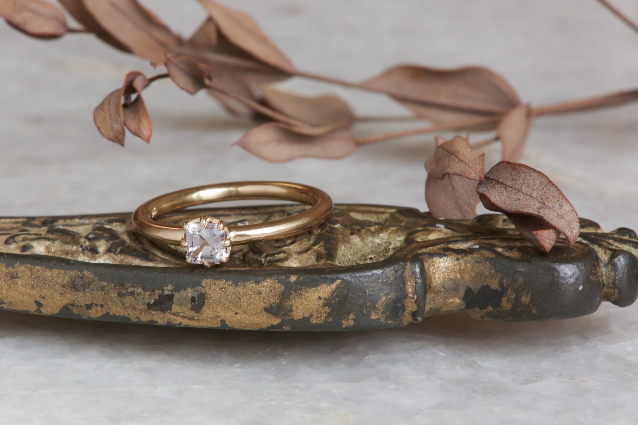 A solitaire ring inspired by antique collet settings in 14 karat yellow gold and a natural rose toned sapphire