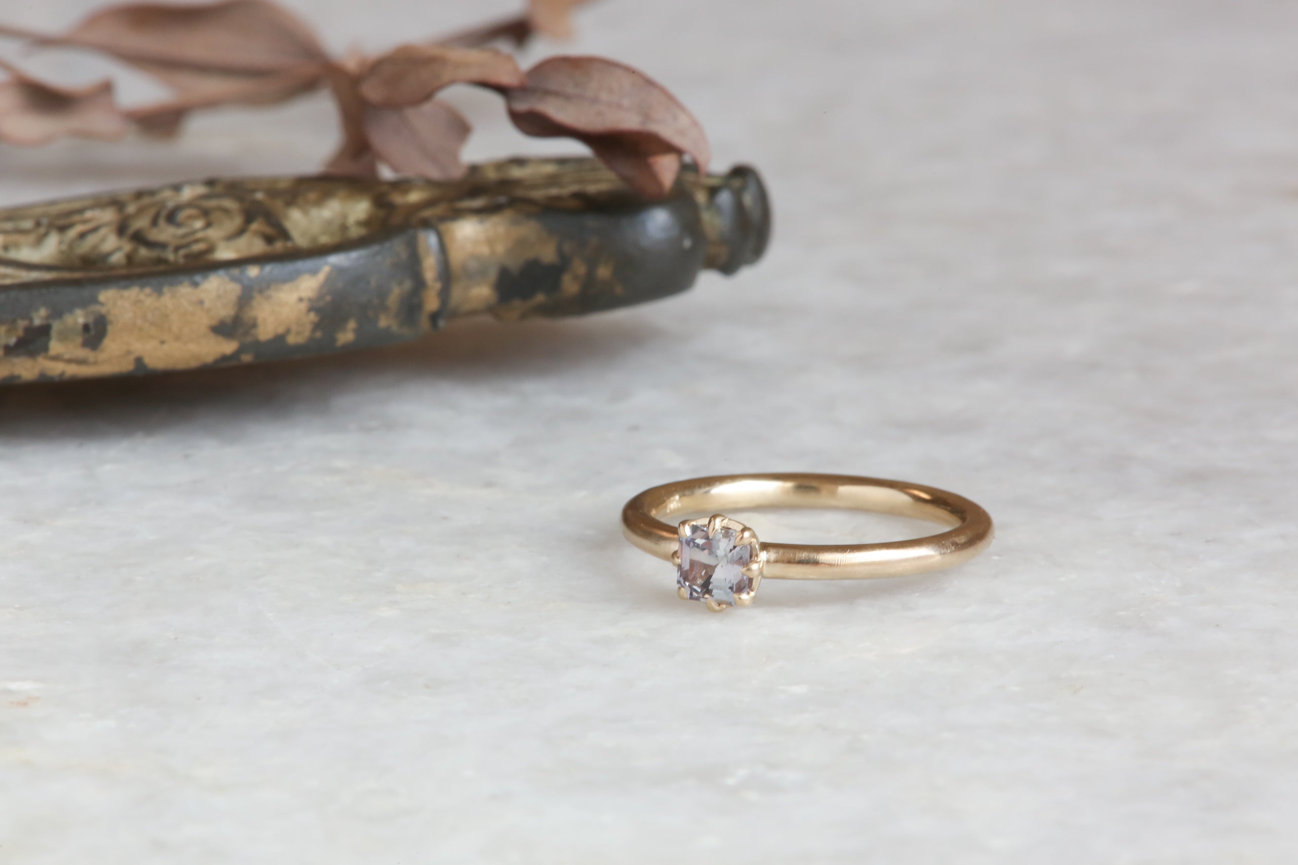 A solitaire ring inspired by antique collet settings in 14 karat yellow gold and a natural rose toned sapphire