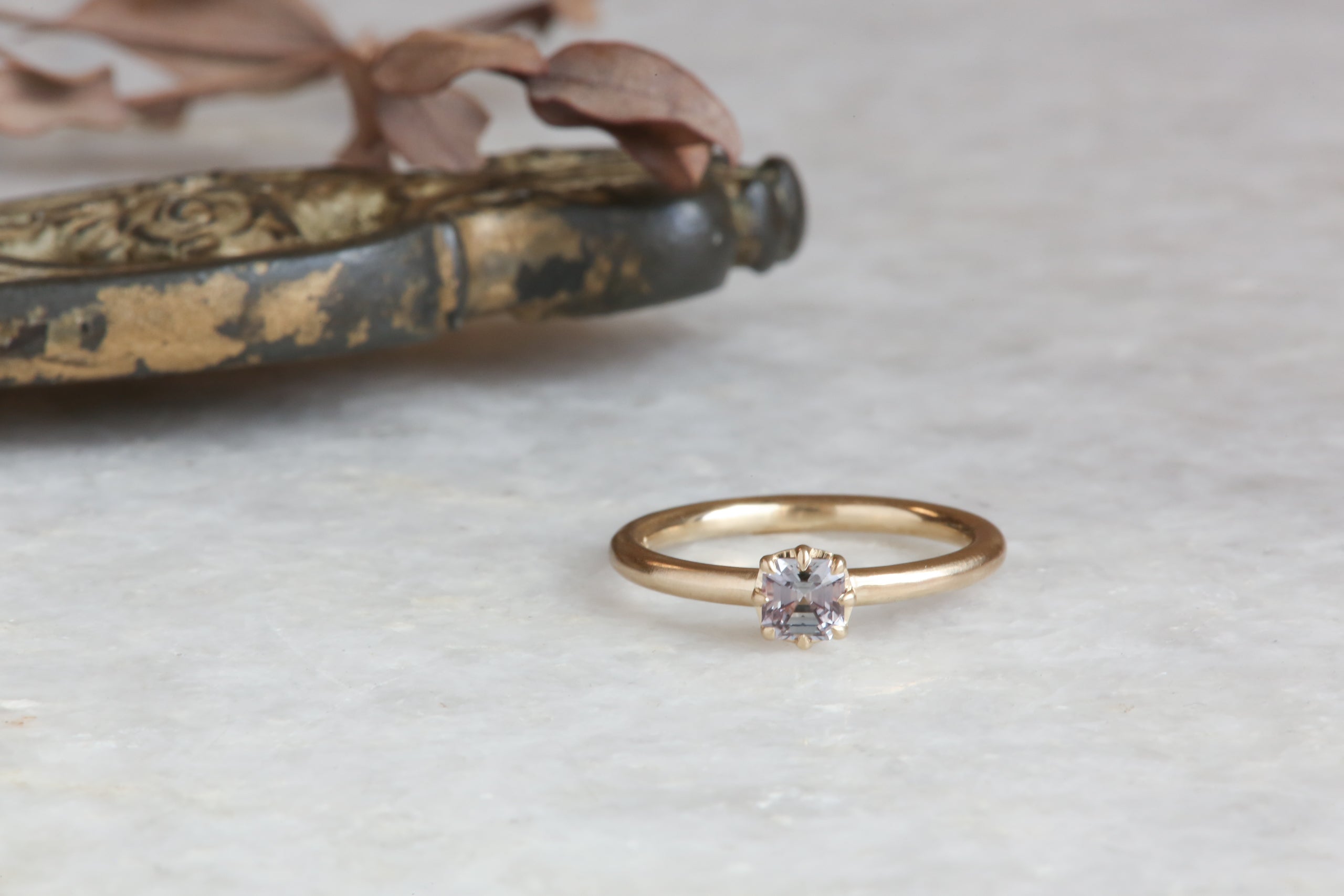 A ready to ship solitaire ring inspired by antique collet settings in 14 karat yellow gold and a natural rose toned Montana sapphire