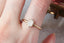Antique style collet setting engagement ring in brushed yellow gold and opalescent diamond.