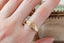 A fantasy inspired wide flower signet band with hand-carved lavender cast in 10 karat yellow gold with a soft brushed finish. Shown on a woman's finger.