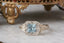 Fantasy elven alternative engagement ring designed and crafted by The North Way Studio. This ready to ship fairytale engagement ring features a diamond halo, a blue princess cut sapphire center, and hand-carved leaves and vines in reclaimed 18 karat white gold.