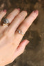 A five stone heirloom engagement ring crafted by The North Way Studio. This nature inspired fantasy engagement ring features five natural rose cut diamonds graduating in size set atop unfurling hand-carved leaves in reclaimed fine golds. The ethereal fairytale ring is shown set in white gold with a yellow gold band. The customizable ring is shown worn on a woman's first finger.