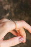 A five stone heirloom engagement ring crafted by The North Way Studio. This nature inspired fantasy engagement ring features five natural rose cut diamonds graduating in size set atop unfurling hand-carved leaves in reclaimed fine golds. The ethereal alternative engagement ring is shown set in white gold with a yellow gold band. The customizable ring is shown worn on a woman's first finger.