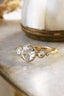A five stone customizable heirloom engagement ring crafted by The North Way Studio. This nature inspired fantasy engagement ring features five natural rose cut diamonds graduating in size set atop unfurling hand-carved leaves in reclaimed fine golds. The ethereal fairytale ring is shown set in white gold with a yellow gold band. 