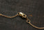 Close-up of a gold lobster clasp and chain on a dark textured wooden surface.