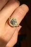 A close-up of a hand wearing a yellow gold halo ring in the Camelot setting by The North Way Studio.