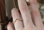 A gold wedding band with tiny diamonds is shown on someone's ring finger at The North Way Studio.