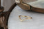 A gold wedding band with tiny diamonds faces left atop a white marble table at The North Way Studio.