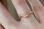 A gold wedding band with tiny leaves and diamonds is shown on someone's finger at The North Way Studio.