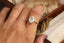 An antique-inspired solitaire ring in whittled 14 karat white gold and 3.03 carat oval brilliant cut lab grown diamond by The North Way Studio. Shown upon the hand. 