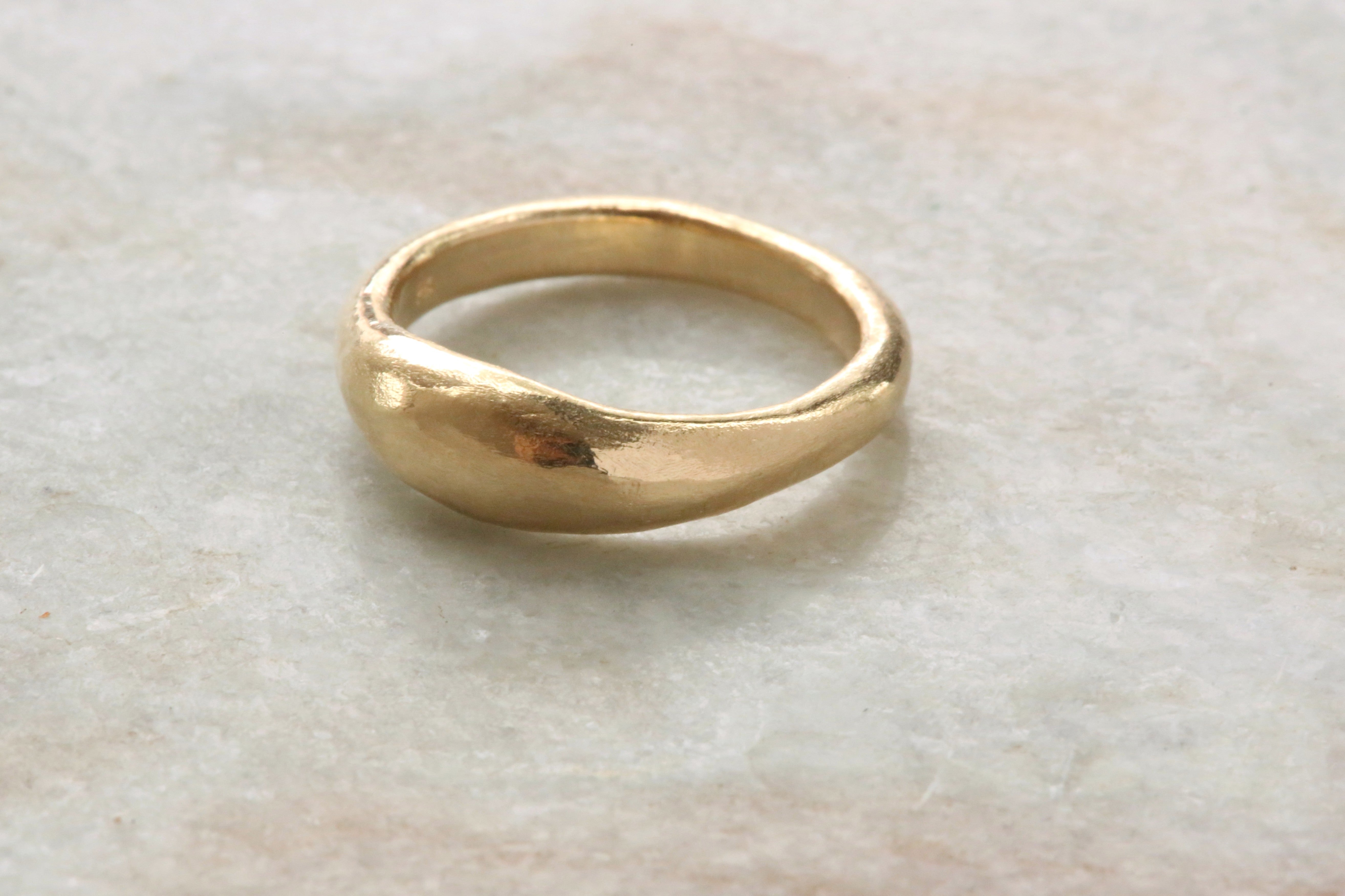 A 14 karat yellow gold signet band with ancient texture. 