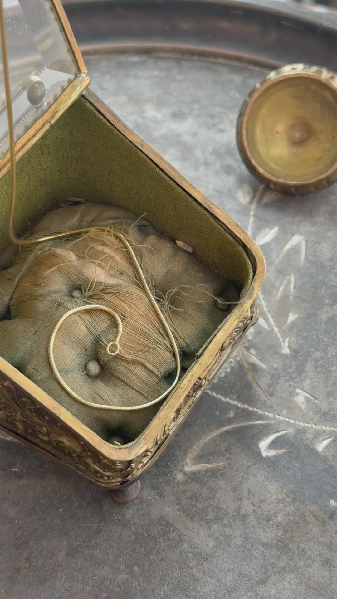 A Snake Chain in solid 14 karat yellow gold slithering into an antique box. 