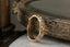 The Gate band is an intricately hand-carved wedding band of woven leaves and arch ways, wrought into reclaimed golds, designed by The North Way Studio. Shown here leaning against an antique brass mirror. 